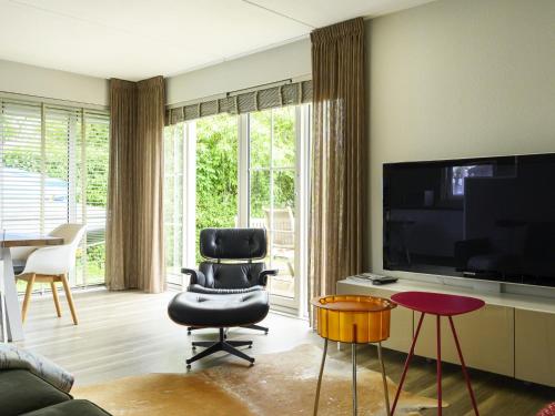a living room with a chair and a television at Holiday Home Bungalowpark It Wiid by Interhome in Eernewoude