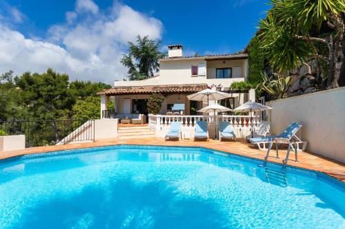 une piscine avec des chaises et une maison dans l'établissement VILLA HATELMA VI4404 By Riviera Holiday Homes, à Nice