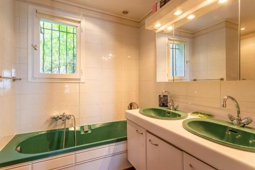 La salle de bains est pourvue de 2 lavabos verts et d'une baignoire. dans l'établissement VILLA HATELMA VI4404 By Riviera Holiday Homes, à Nice