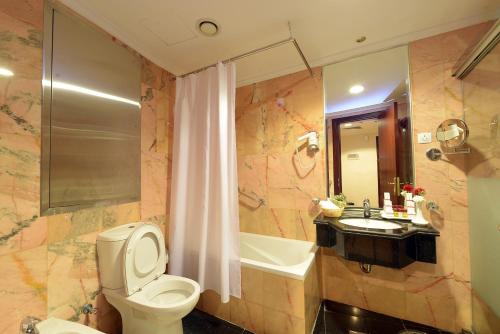 a bathroom with a toilet and a sink and a tub at Deyar Al Eiman Hotel in Al Madinah