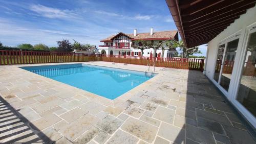 une piscine devant une maison dans l'établissement Urrugne, Croix des bouquets, au 1er étage d'une bâtisse Basque, APPT 10 pers avec piscine, à Urrugne