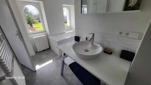 une salle de bain blanche avec un lavabo et un miroir dans l'établissement Urrugne, Croix des bouquets, au 1er étage d'une bâtisse Basque, APPT 10 pers avec piscine, à Urrugne