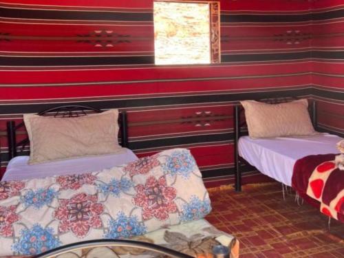 two beds in a room with red striped walls at Wadi Rum Desert Adventures in Wadi Rum