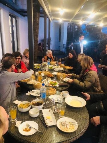 a group of people sitting around a table eating food at Pema Thang Guest House Mcleodganj in Dharamshala