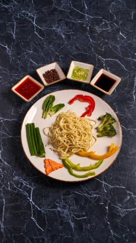 a plate of food with noodles and vegetables and sauce at Pema Thang Guest House Mcleodganj in Dharamshala