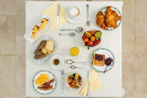 a white table topped with plates of breakfast foods at Hotel Vecchia Marina in Àrbatax