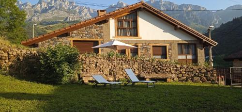 two chairs and an umbrella in front of a house at Casa Vacacional La Pedrera in Baró