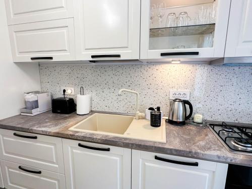 a kitchen with white cabinets and a sink at ACM Premium 3 camere Apartament elegant in Voluntari