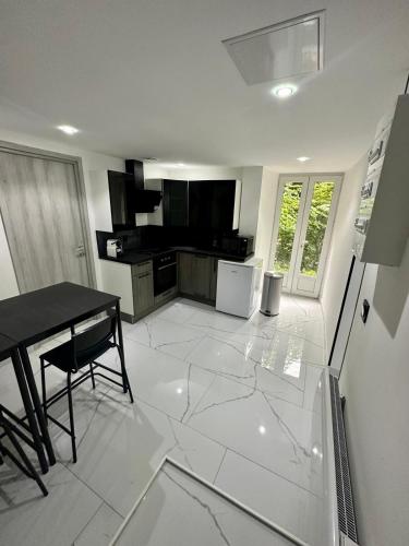 Il comprend une cuisine dotée de carrelage blanc et d'une table. dans l'établissement Suite Cosy Chic, à Saint-Claude