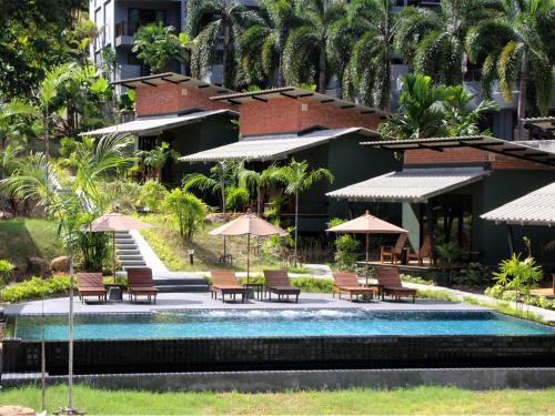 a pool with chairs and umbrellas in front of a building at Eco Inn Cottage by Aonang Hill in Ao Nang Beach
