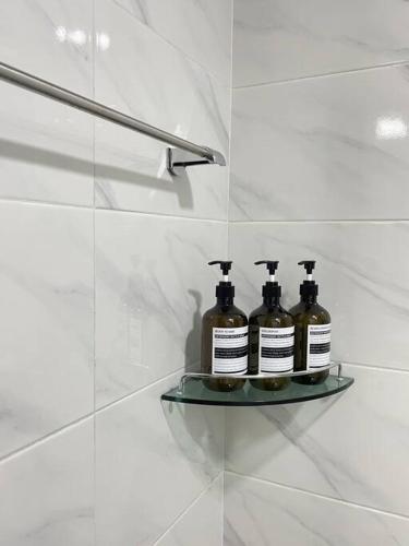 three bottles of soap on a glass shelf in a bathroom at Draw Gwangju in Gwangju