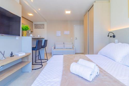 a bedroom with a large white bed and a kitchen at Allure Residence by Carpediem in Recife