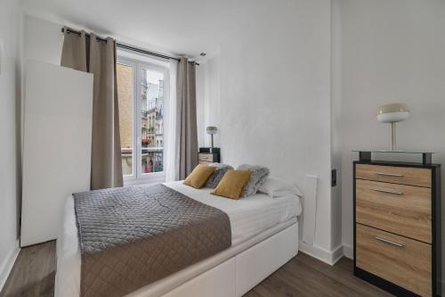 une chambre blanche avec un lit et une fenêtre dans l'établissement Par Amour, à Paris