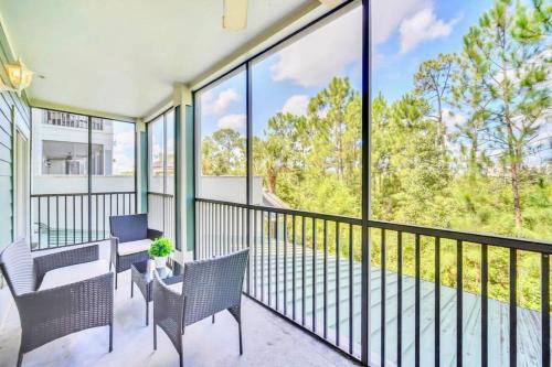 a balcony with chairs and tables and large windows at Modern 3BR Condo Near Disney- Pool and Hot Tub in Orlando