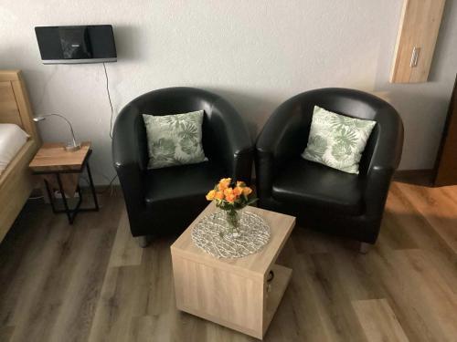 2 sillas de cuero negro y una mesa en la sala de estar en Ferienwohnung Harzer Sonnenbaum, en Sankt Andreasberg