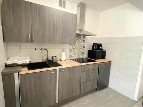 La cuisine est équipée de placards en bois, d'un évier et d'un four micro-ondes. dans l'établissement BEL AIR - Studio, Proche centre, WIFI, Climatisation, à Antibes