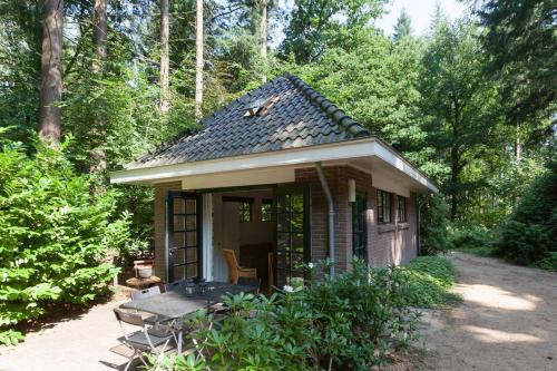a small house with a porch in the woods at Bos Huisje in Putten