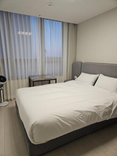 a large white bed in a room with a window at Songdo Halla Westernpark-SeaViewRoom Hotel-바다전망 in Incheon