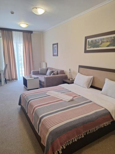 a hotel room with a bed and a couch at Garni Hotel Ema in Kragujevac