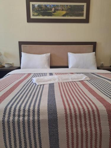 a bed with a striped blanket on top of it at Garni Hotel Ema in Kragujevac