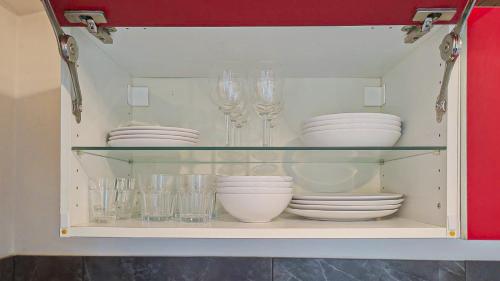 une armoire remplie de vaisselle et de verres à vin dans l'établissement Jean Medecin - AC, 2pers, Hyper center, à Nice