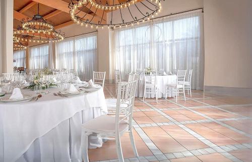 a dining room with white tables and chairs and a chandelier at Impressive Playa Granada Golf in Motril