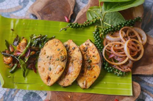 a green plate of food with sausages and vegetables at Mountain Club Resort Munnar in Chinnakanal
