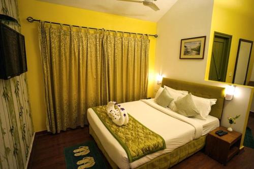 a bedroom with a large bed with yellow walls at Mountain Club Resort Munnar in Chinnakanal