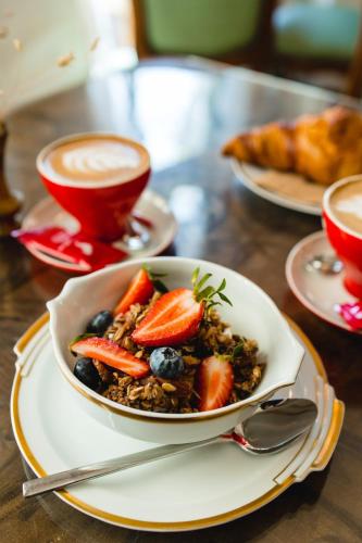 a bowl of fruit on a table with two cups of coffee at Royal Hotel in Varna City