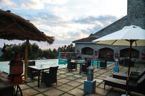a patio with tables and chairs next to a pool at Mountain Club Resort Munnar in Chinnakanal