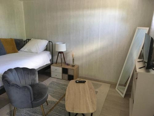 une chambre avec un lit, une chaise et une table dans l'établissement Au calme, proche gare, à Brive-la-Gaillarde