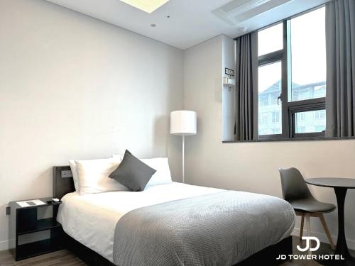 a bedroom with a bed and a table and a window at JD Tower Hotel in Seoul