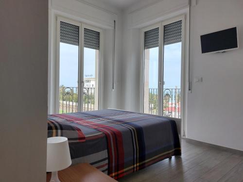 a bedroom with a bed and windows with a tv at Casa Vacanze CuprAmare in Cupra Marittima