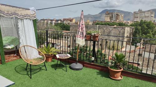 a balcony with chairs and an umbrella and plants at I Sollazzi in Palermo