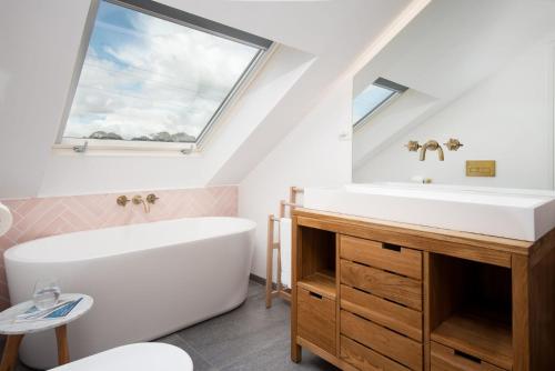 Un baño con bañera, lavabo y ventana. en Art House Seahouses, en Seahouses