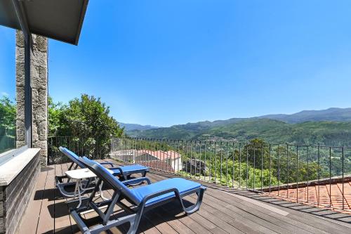 a deck with two chairs and a table with a view at Casas das Olas in Arcos de Valdevez