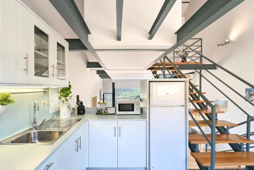 a kitchen with white cabinets and a spiral staircase at Casas das Olas in Arcos de Valdevez