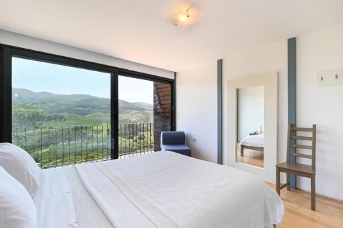 a bedroom with a white bed and a large window at Casas das Olas in Arcos de Valdevez