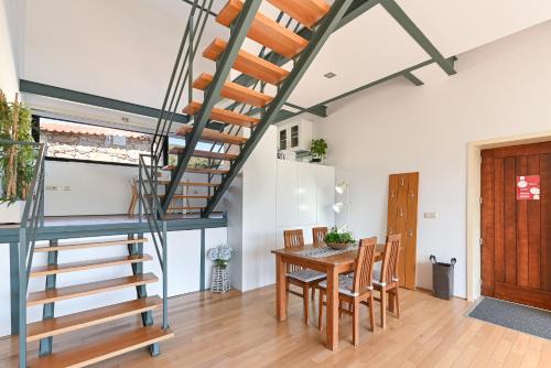 a dining room with a wooden table and a spiral staircase at Casas das Olas in Arcos de Valdevez
