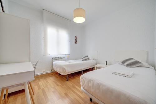 a white room with two beds and a window at Vistabella 1 by Clabao in Pamplona