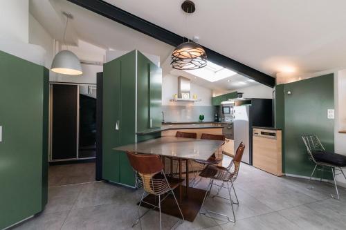 une cuisine avec des armoires vertes, une table et des chaises dans l'établissement Chartreuse du Parc - Quartier Caudéran, chic et calme, Grande Terrasse 2 chambres avec Parking, à Bordeaux