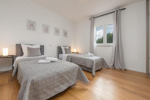 Un dormitorio con dos camas y una ventana. en Villa Zeleni gaj ZadarVillas, en Donje Raštane