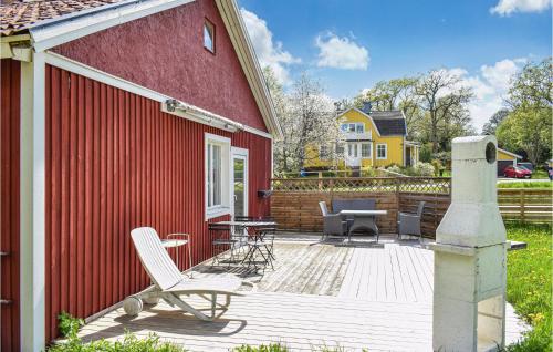 a red house with a deck with chairs and a table at 3 Bedroom Beautiful Home In Blankaholm in Blankaholm