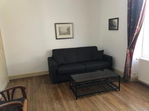 a living room with a black couch and a coffee table at Gite le Vaudésir in Ligny-le-Châtel