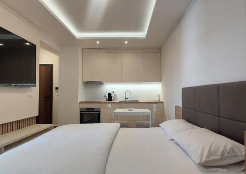 a bedroom with a white bed and a kitchen at Stan na dan Borik Banja Luka in Banja Luka