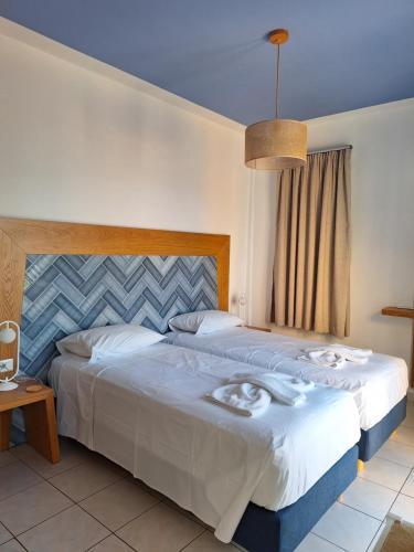 a bedroom with a large bed with white sheets at Artemis Apartments in Kalyves