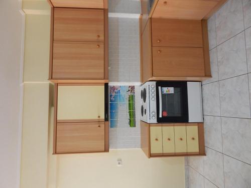 a kitchen with wooden cabinets and a microwave at Angela's Apartment with beautiful balcony view in Agios Konstantinos Fthiotida