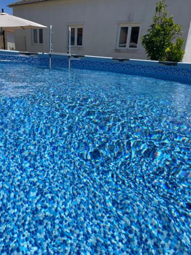 a swimming pool with blue water in front of a house at Casa da Abrunheira in Ramalhal