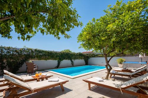 einen Hinterhof mit Pool, Stühlen und einem Baum in der Unterkunft Sunshine Holiday Home in Kaštela