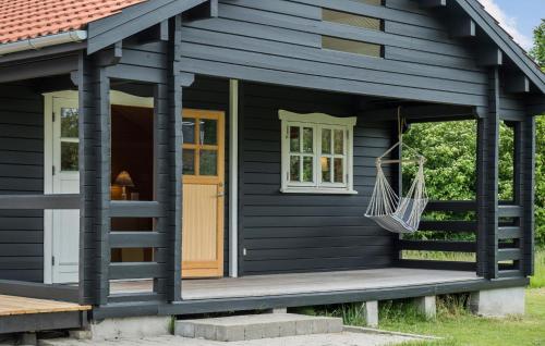 una casa negra con un porche y un columpio en Nice Home In Store Fuglede With Wifi, en Store Fuglede